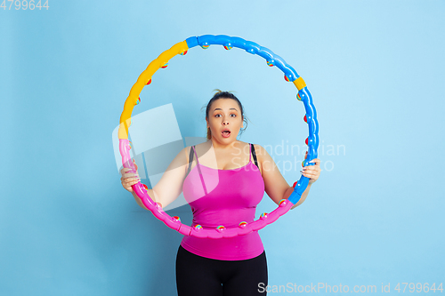 Image of Young caucasian plus size female model\'s training on blue background