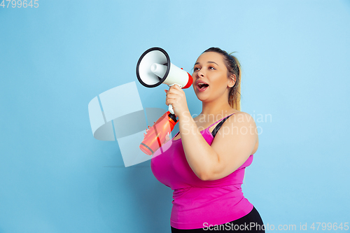 Image of Young caucasian plus size female model\'s training on blue background