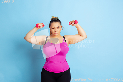 Image of Young caucasian plus size female model\'s training on blue background