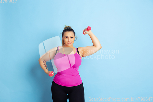 Image of Young caucasian plus size female model\'s training on blue background