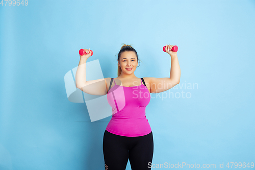 Image of Young caucasian plus size female model\'s training on blue background