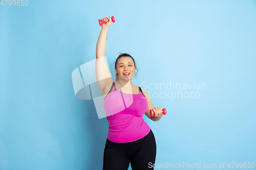 Image of Young caucasian plus size female model\'s training on blue background