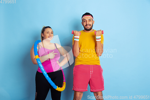 Image of Young pretty caucasian couple in bright clothes training on blue background