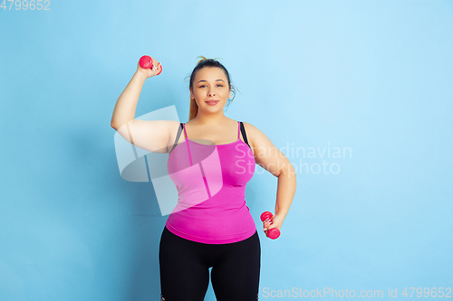 Image of Young caucasian plus size female model\'s training on blue background