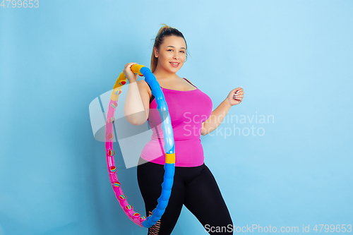 Image of Young caucasian plus size female model\'s training on blue background