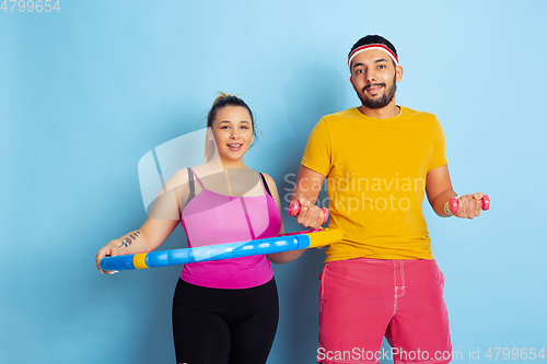 Image of Young pretty caucasian couple in bright clothes training on blue background