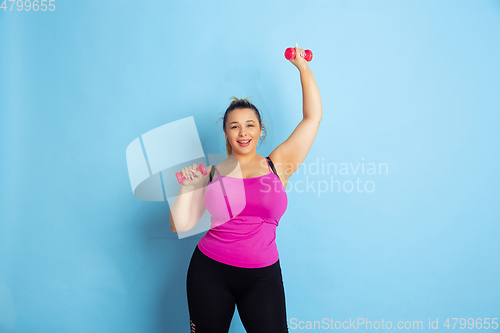 Image of Young caucasian plus size female model\'s training on blue background