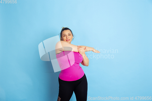 Image of Young caucasian plus size female model\'s training on blue background