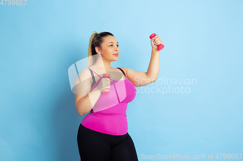 Image of Young caucasian plus size female model\'s training on blue background