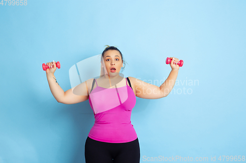 Image of Young caucasian plus size female model\'s training on blue background