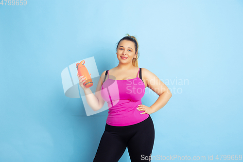 Image of Young caucasian plus size female model\'s training on blue background