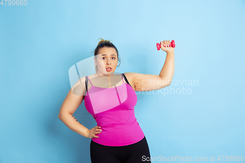 Image of Young caucasian plus size female model\'s training on blue background
