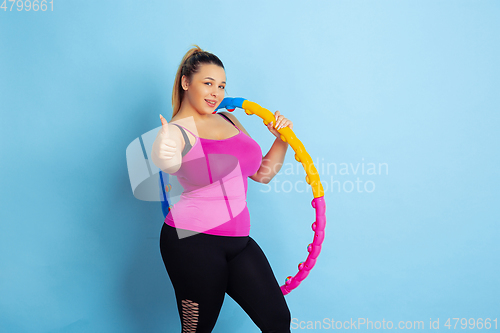 Image of Young caucasian plus size female model\'s training on blue background