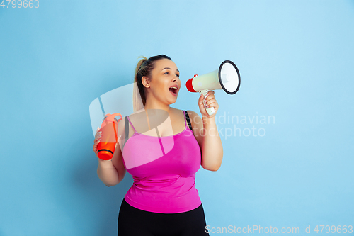 Image of Young caucasian plus size female model\'s training on blue background