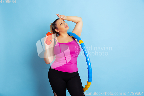 Image of Young caucasian plus size female model\'s training on blue background