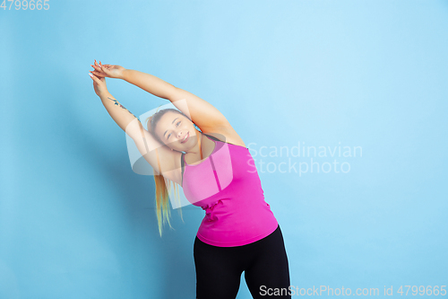 Image of Young caucasian plus size female model\'s training on blue background