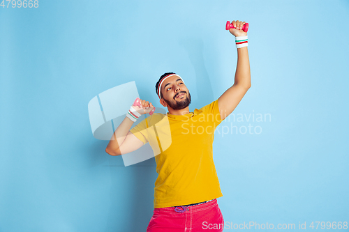 Image of Young caucasian man in bright clothes training on blue background