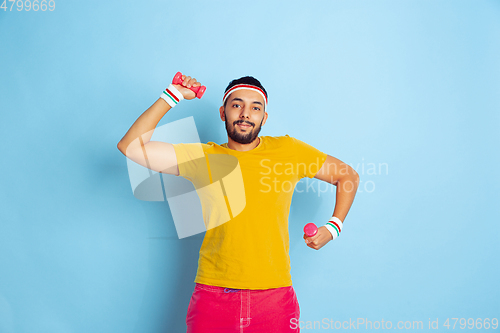 Image of Young caucasian man in bright clothes training on blue background