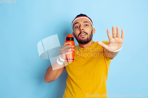 Image of Young caucasian man in bright clothes training on blue background