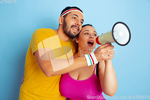 Image of Young pretty caucasian couple in bright clothes training on blue background