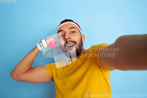 Image of Young caucasian man in bright clothes training on blue background