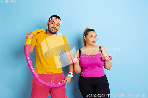 Image of Young pretty caucasian couple in bright clothes training on blue background