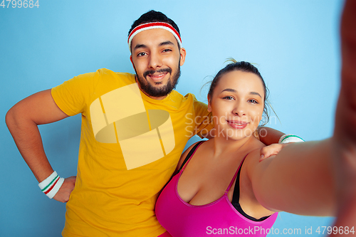 Image of Young pretty caucasian couple in bright clothes training on blue background