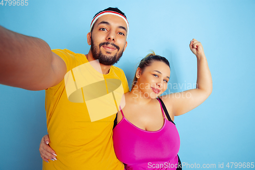 Image of Young pretty caucasian couple in bright clothes training on blue background