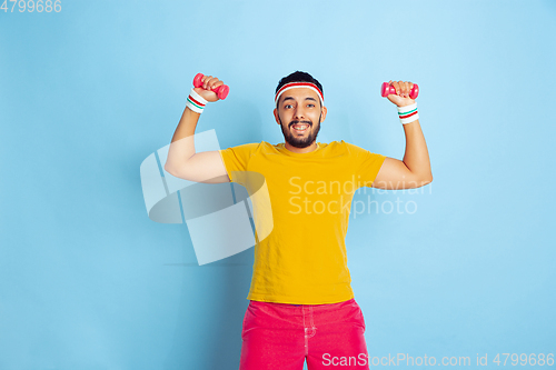 Image of Young caucasian man in bright clothes training on blue background