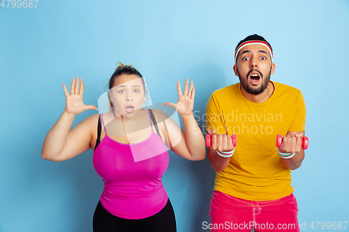 Image of Young pretty caucasian couple in bright clothes training on blue background