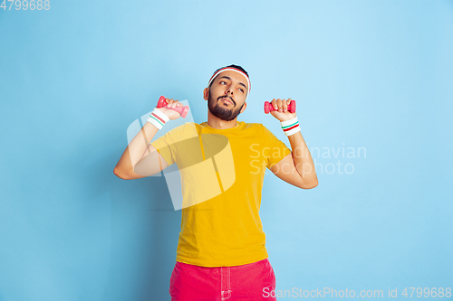 Image of Young caucasian man in bright clothes training on blue background