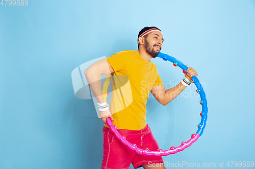 Image of Young caucasian man in bright clothes training on blue background