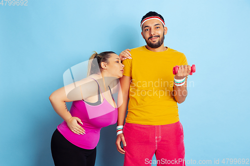 Image of Young pretty caucasian couple in bright clothes training on blue background