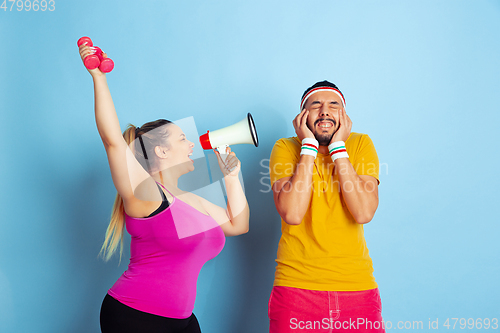 Image of Young pretty caucasian couple in bright clothes training on blue background