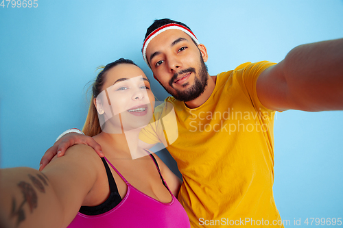 Image of Young pretty caucasian couple in bright clothes training on blue background