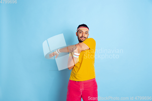 Image of Young caucasian man in bright clothes training on blue background