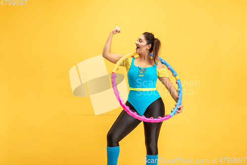 Image of Young caucasian plus size female model\'s training on yellow background