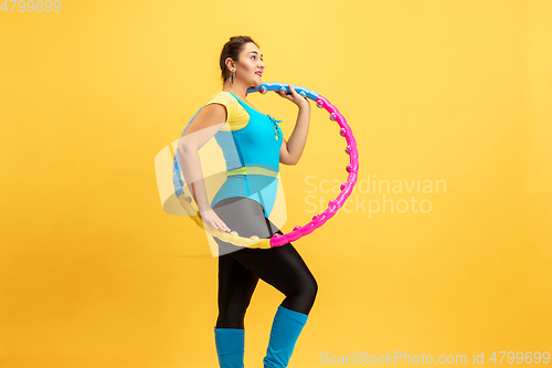 Image of Young caucasian plus size female model\'s training on yellow background