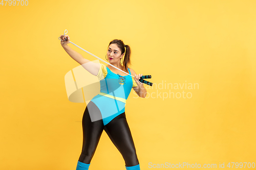 Image of Young caucasian plus size female model\'s training on yellow background