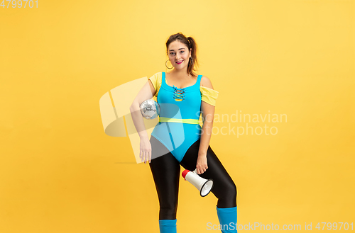 Image of Young caucasian plus size female model\'s training on yellow background