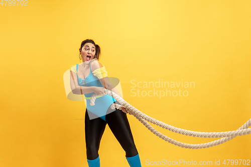 Image of Young caucasian plus size female model\'s training on yellow background