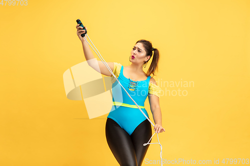 Image of Young caucasian plus size female model\'s training on yellow background