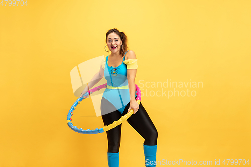 Image of Young caucasian plus size female model\'s training on yellow background