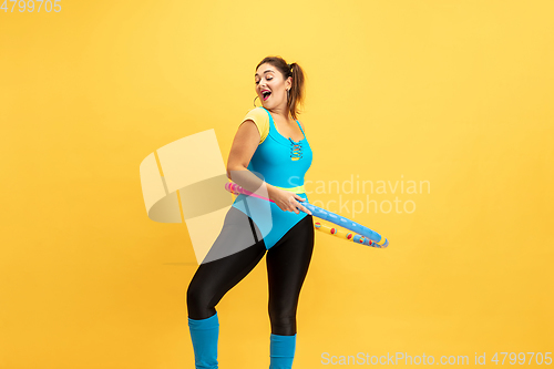 Image of Young caucasian plus size female model\'s training on yellow background
