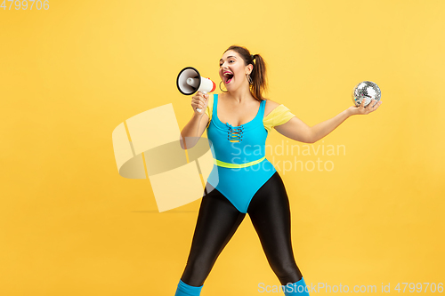 Image of Young caucasian plus size female model\'s training on yellow background