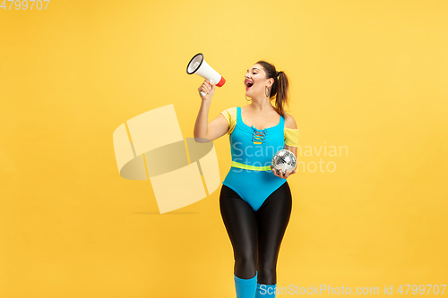 Image of Young caucasian plus size female model\'s training on yellow background