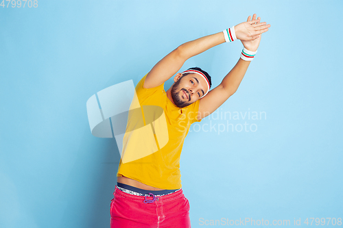 Image of Young caucasian man in bright clothes training on blue background