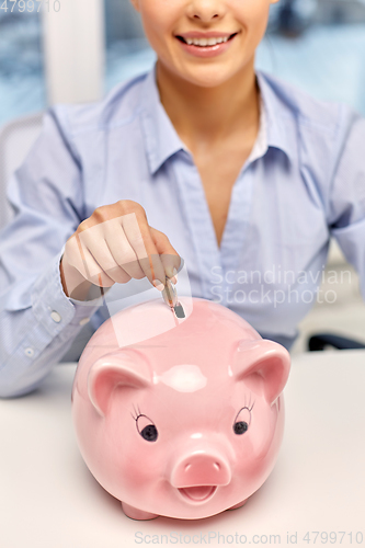 Image of businesswoman with piggy bank and coin at office