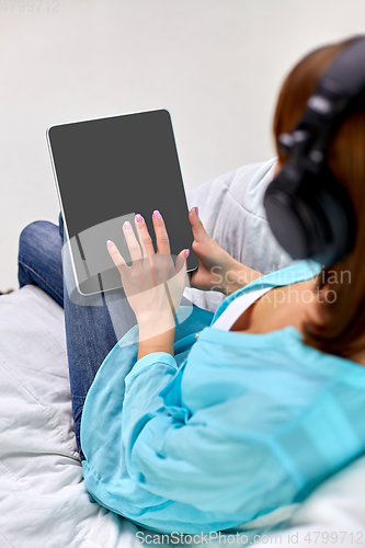 Image of woman with tablet pc and headphones at home