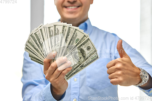 Image of smiling businessman with money showing thumbs up